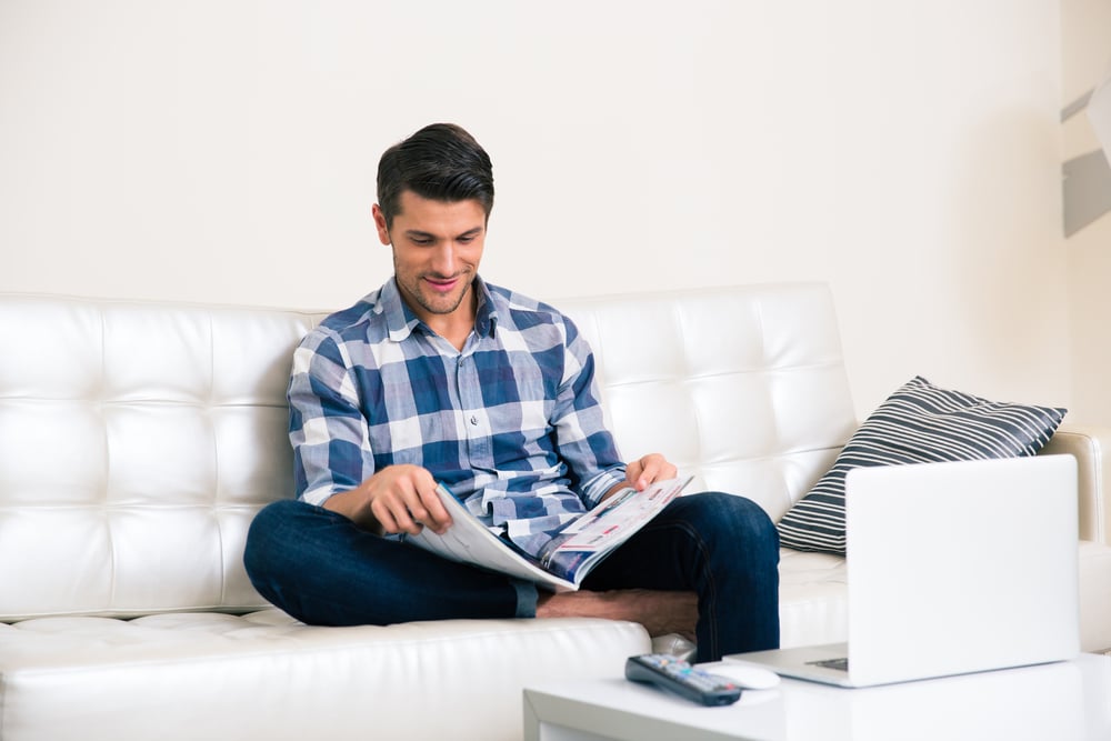 Portrait of a man reading magazine on the sofa at home